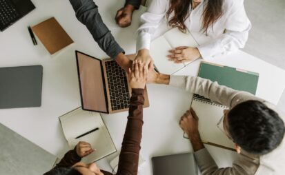 Image of a team connecting hands over a laptop